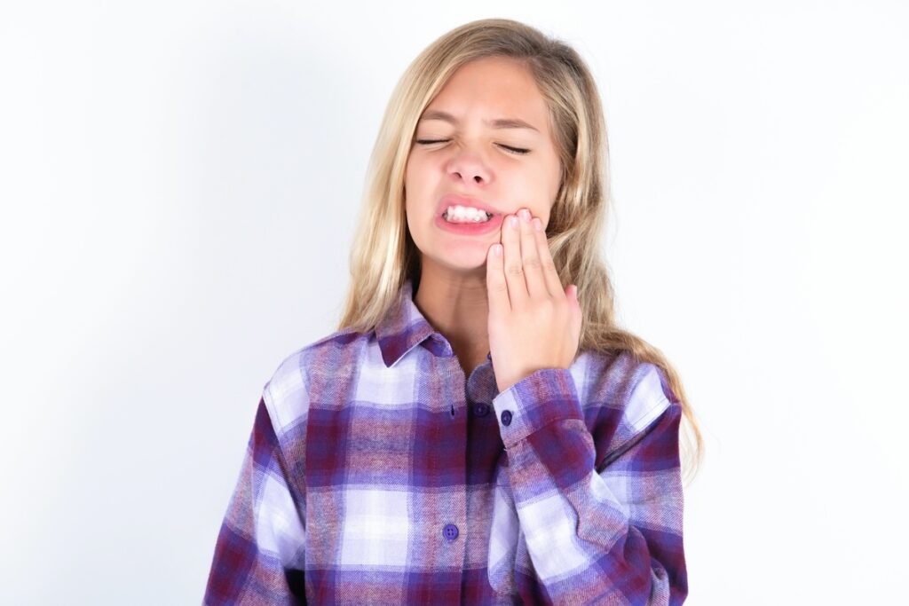 MODEL touching mouth with hand with painful expression because of toothache or dental illness on teeth.